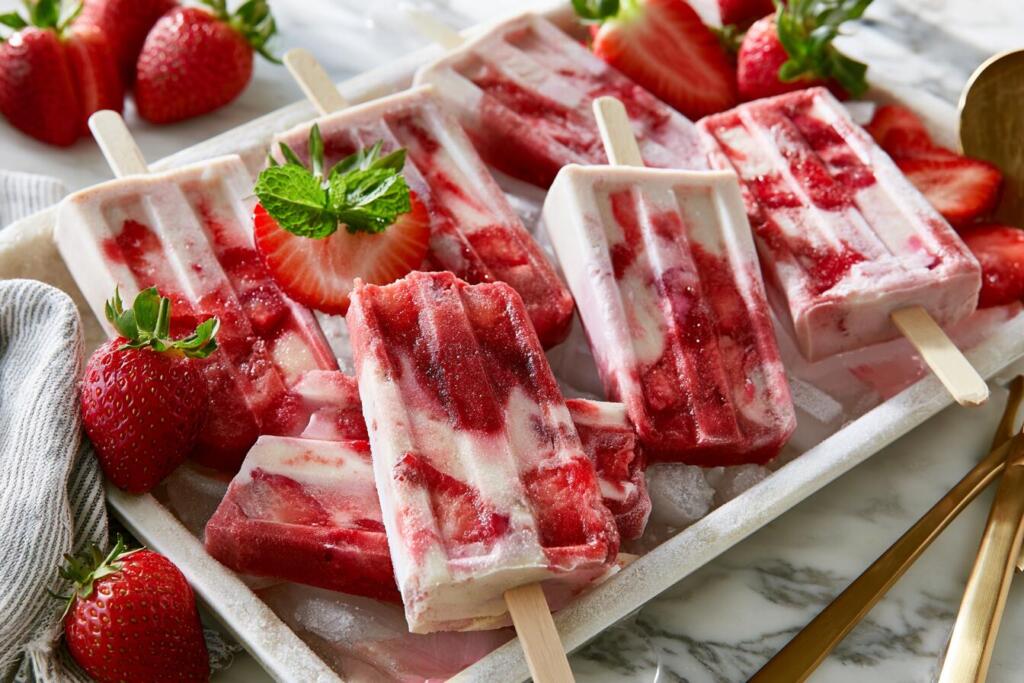 Plated strawberry protein popsicles on a chilled tray with fresh strawberry chunks and mint
